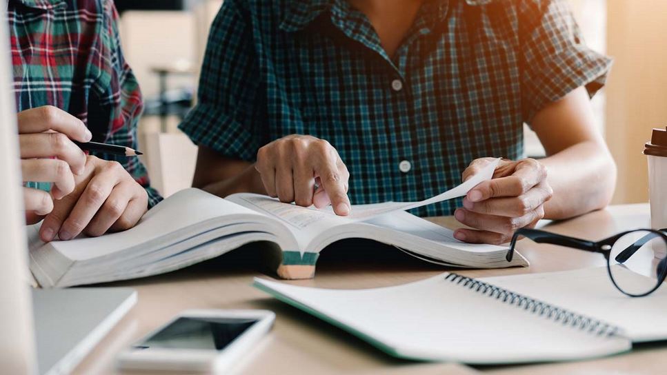 image of students hovering over a texbook