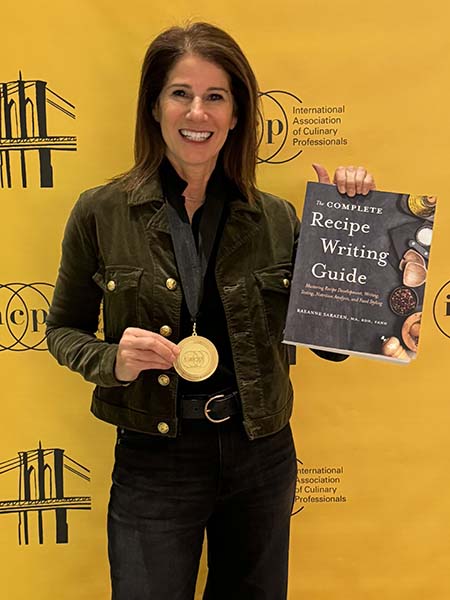 Raeanne Sarazen posing with IACP Cookbook Award and book